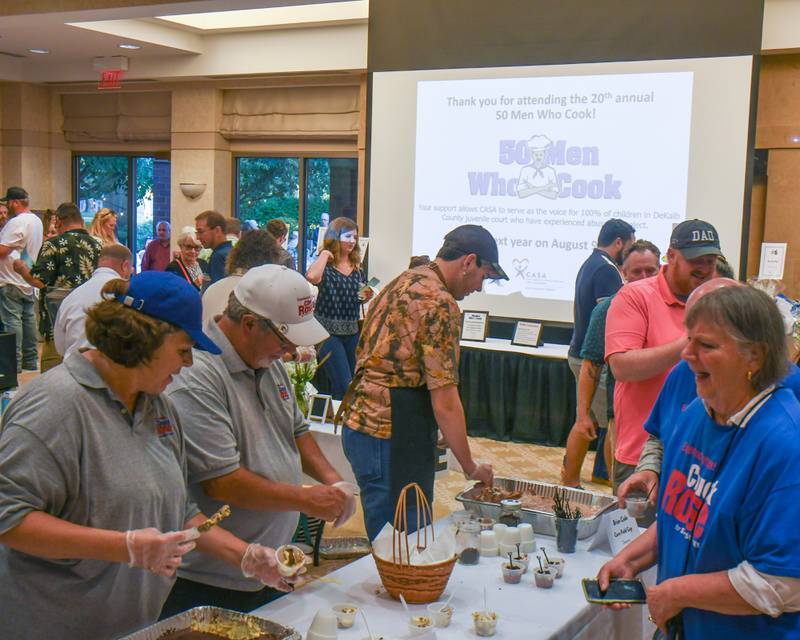 Volunteer cooks portion out food that they prepared during the 20th anniversary of 50 Men Who Cook, an annual fundraiser hosted by CASA DeKalb County at the Barsema Alumni and Visitors Center at Northern Illinois University in DeKalb on Saturday, Aug. 10, 2024.