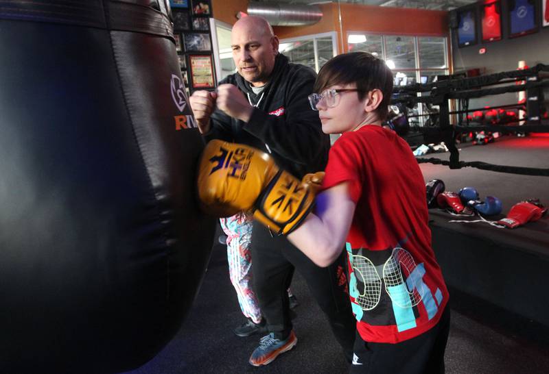 Larry Lentz, head coach, works with Jett Pagliocca, 12, of Vernon Hills on a bag drill Feb. 17 during the Kids Boxing class at the Conquer Fight Club in Mundelein. The class is held at 5 p.m. on Monday, Wednesday and Friday.