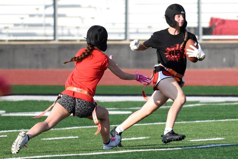 Bradley-Bourbonnais' Maddie Watters, right, attempts to outrun senior teammate Audrey Conradi during the school's flag football camp Wednesday, July 2, 2025.