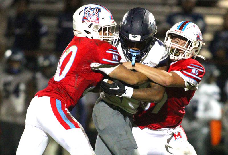 Marian Central’s Abel Arce, left, and Sam Mahoney, right, tackle Chicago Hope’s Jamari West  in varsity football at Woodstock Friday night.