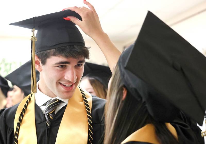 Alyssa Akers gives Dawson Alexander a hand with his graduation cap before commencement ceremonies Sunday, May 28, 2023, at Sycamore High School.