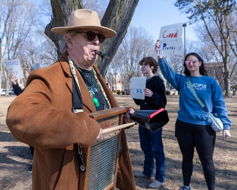Protester blows kazoo whilst hitting cowbell at the 'Pretti good time for a Protest' on Feb. 15, 2026 at Washington Square Park in Ottawa.