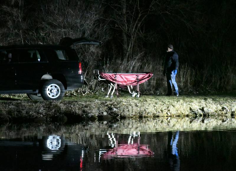 Ogle County Coroner Lou Finch stands by an empty gurney as he waits for the body to be brought to the shore at Oppold Marina.