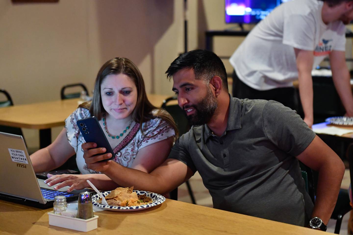 Illinois 43rd  District State Senate Candidate Rachel Ventura and Joliet township supervisor Angel Contreras look at the polls during a watch party Tuesday, June 28, 2022 ,at Vella's Tap in Joliet