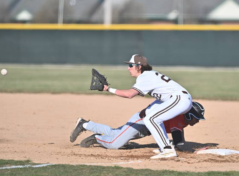 Joliet Catholic's Jake Troyner attempts to tag the runner on first base during the non-conference game against Minooka on Monday, March. 11, 2024, at Joliet.