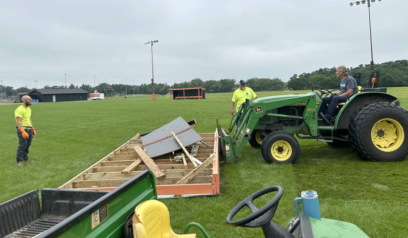 Byron School District employees Nick Sapoznick, Jim Getzelman, and Terry Wilken remove one of the wooden team shelters from the high school soccer field on Tuesday, July 16, 2024.