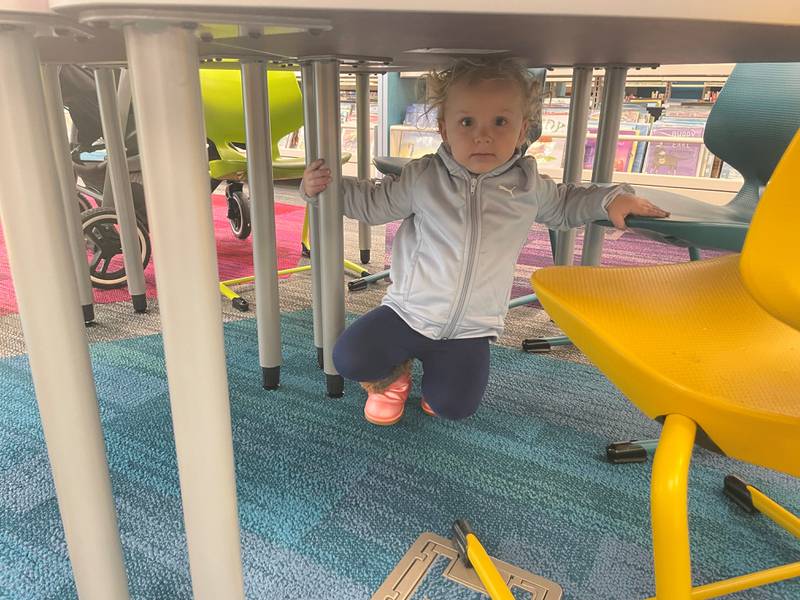 Algonquin Area Public Library's Eastgate Branch reopened Jan. 6, 2025, after a five-month for a $6 million renovation. Here, 2-year-old Rayna Haun of Algonquin hides under a table in the renovated youth services section of the library's lower level.