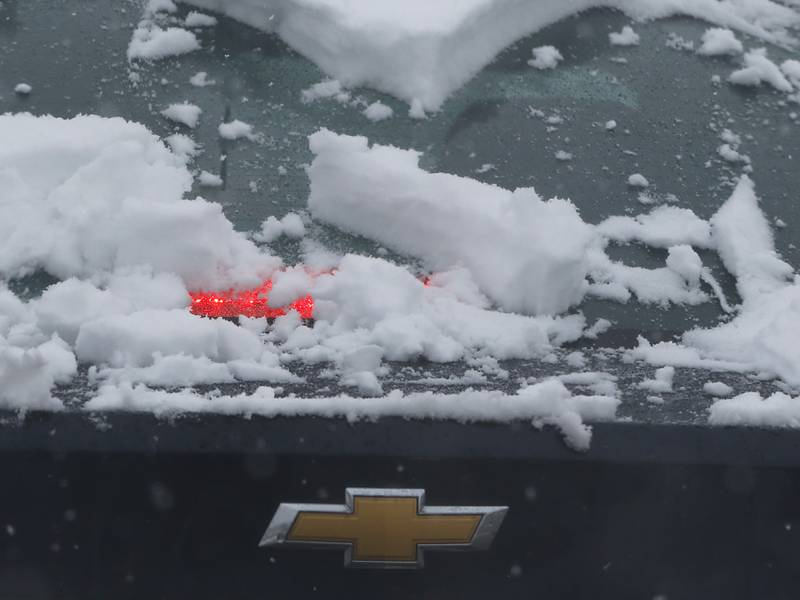 Snow covers a brake light as a car waits for a traffic light to change on Wednesday, Jan. 25, 2023, in McHenry, after snow fell throughout the morning.