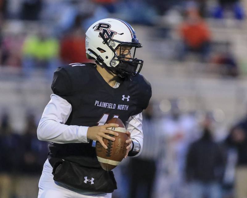 Plainfield North's Adam Smith (11) drops back to pass during football game between Oswego at Plainfield North.  March 26.