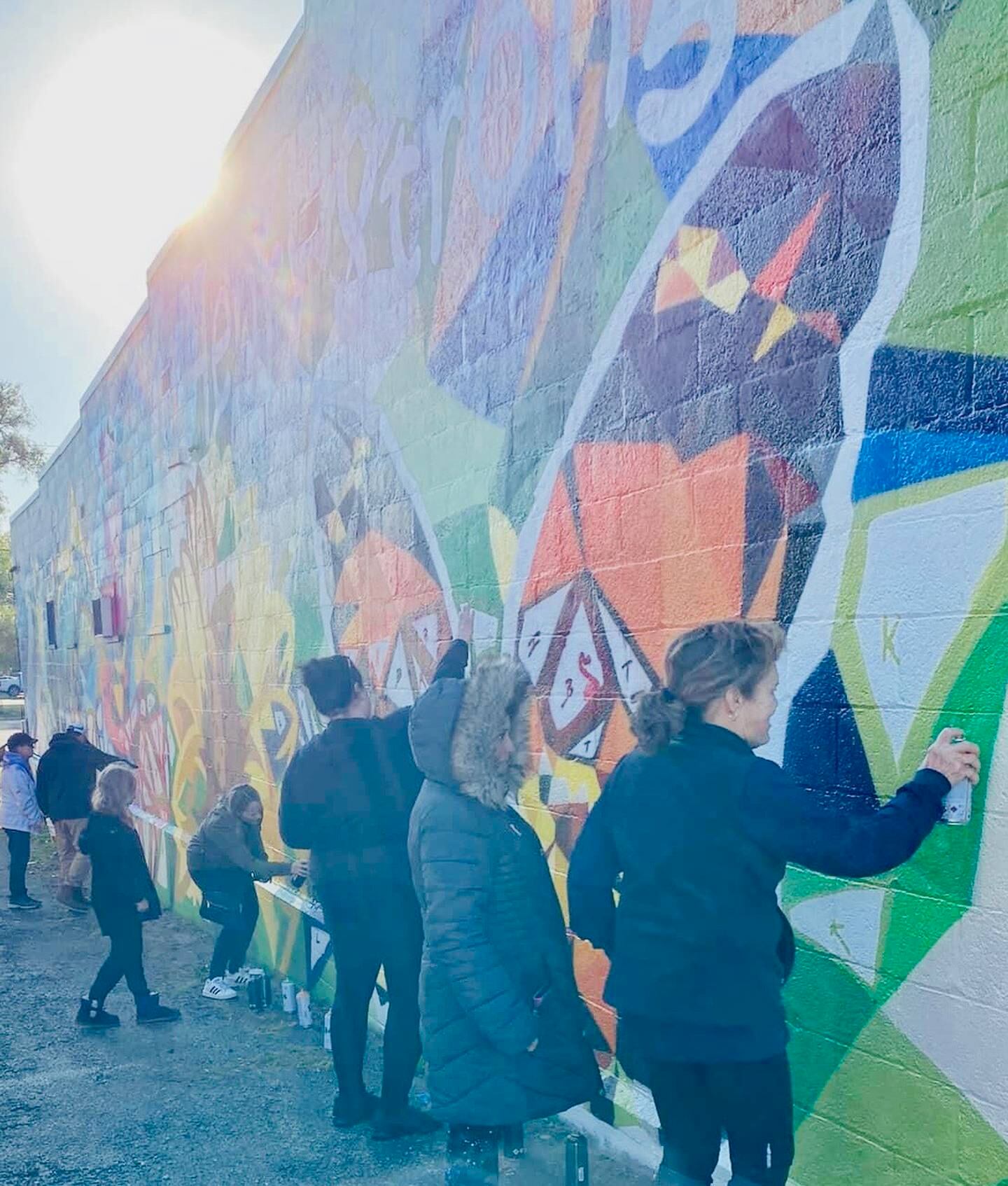 Volunteers add spray paint to the downtown McHenry mural on Saturday, Oct. 22, 2022. Completion on the art installation is expected this week.