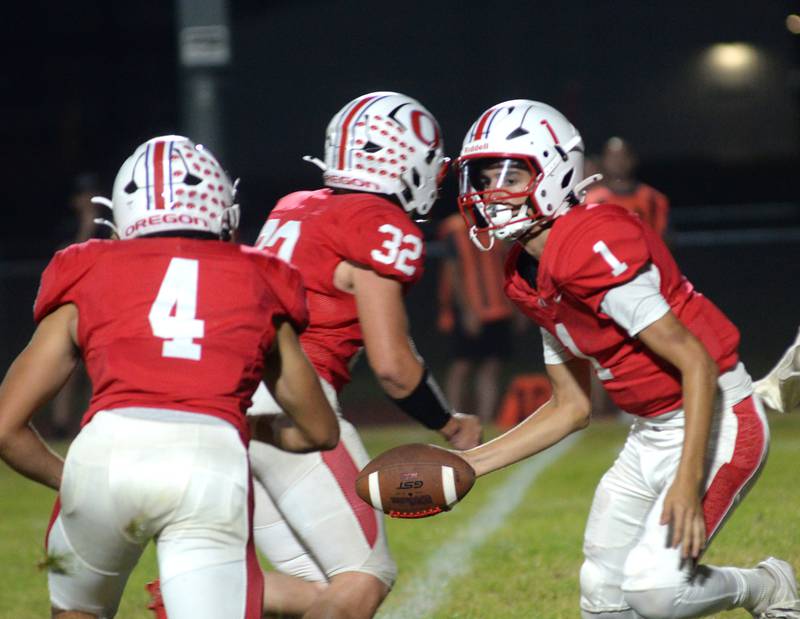 Oregon quarterback Benny Olalde (1) looks to hand the ball off to Jakobi Donagen (4) as Jakob Moser (32) prepares to block against Rock Falls on Friday, Sept. 19, 2025 at Landers-Loomis Field in Oregon.