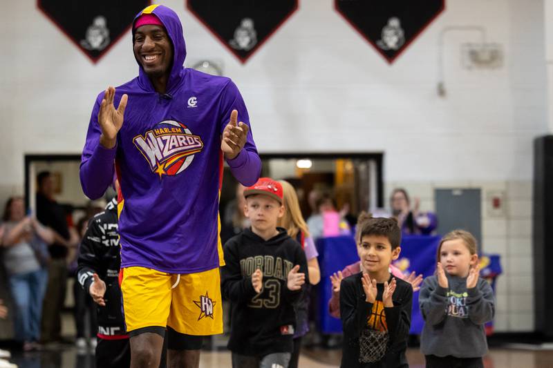 Kamil “Dragon” Brown (77) of the Harlem Wizards claps during his introduction with an entourage of fans behind him on Wednesday, April 16, 2025 at Woodland High School in Streator.