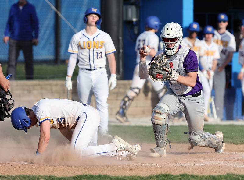 Downers Grove North catcher Jimmy Janicki show the umpire the ball after tagging out Lyons Township's James Georgelos at home plate during the boys varsity baseball game between Lyons Township and Downers Grove North high schools in Western Springs on Tuesday, April 11, 2023.