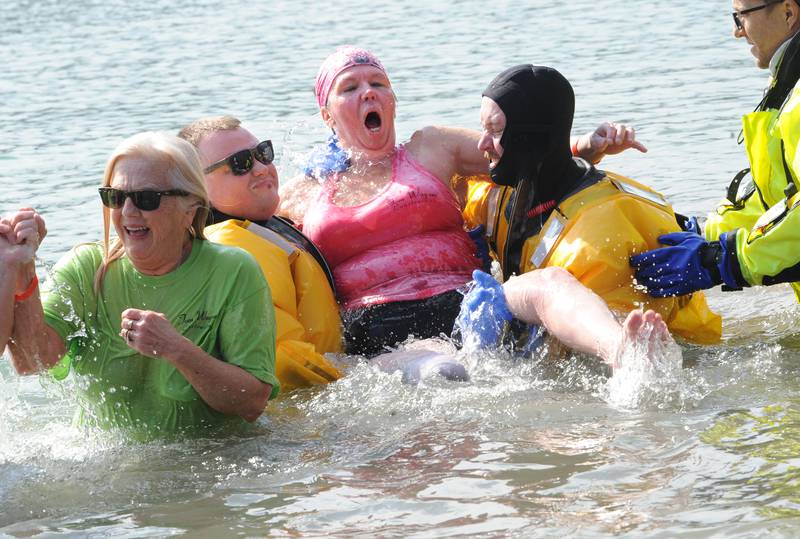 With assistance from Sandwich Fire Protection District's Mitch Morel (left) and Little Rock-Fox F.P.D.'s Mitch Johns, amputee Cary Wagner reacts to the water during the annual Polar Plunge to support Special Olympics Illinois at Siver Springs State Park's Loon Lake on Sunday, Mar. 5, 2023.
