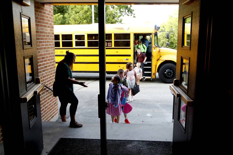 Library assistant Renee Hagan greats students as they get off the school bus Monday morning, August 15, 2022, during the first day of school at District 200’s Greenwood Elementary School. Many McHenry County area schools return to session this week.