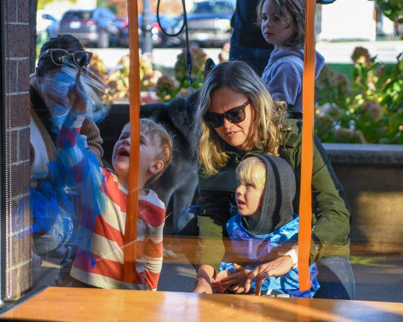 Michelle Nalepa helps her son Jackson Nalepa, 3 years old, of Downers Grove and friend Ethan Ketterhagen, 3 years old, of Downers Grove paint during the Halloween Window painting in downtown Downers Grove on Saturday Oct. 21, 2023.