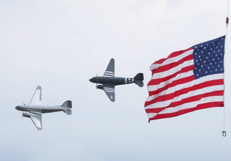A pair of C-47 airplanes fly next to an American Flag during the annual TBM Reunion and Airshow on Friday, May 20, 2022 at the Illinois Valley Regional Airport in Peru.