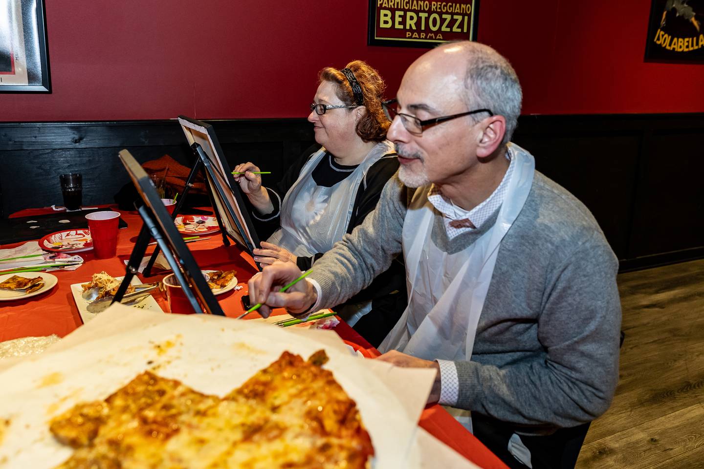 New Lenox residents Laura and David Gardner enjoy pizza and painting during Divine Design Paint Studio's paint party at Papa Joe's in Lockport on Feb. 6, 2025.