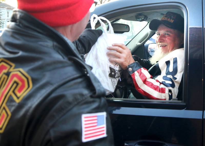 Volunteer James Brantley, a US Marine Corps veteran from DeKalb, hands a meal to Ed Bauer, a US Army veteran from Waterman, Friday, Nov. 11, 2022, during a Veterans Day drive-thru dinner event hosted by the DeKalb and Sycamore Elks Clubs at the Lincoln Inn at Faranda's. All veterans received free meals during the event.
