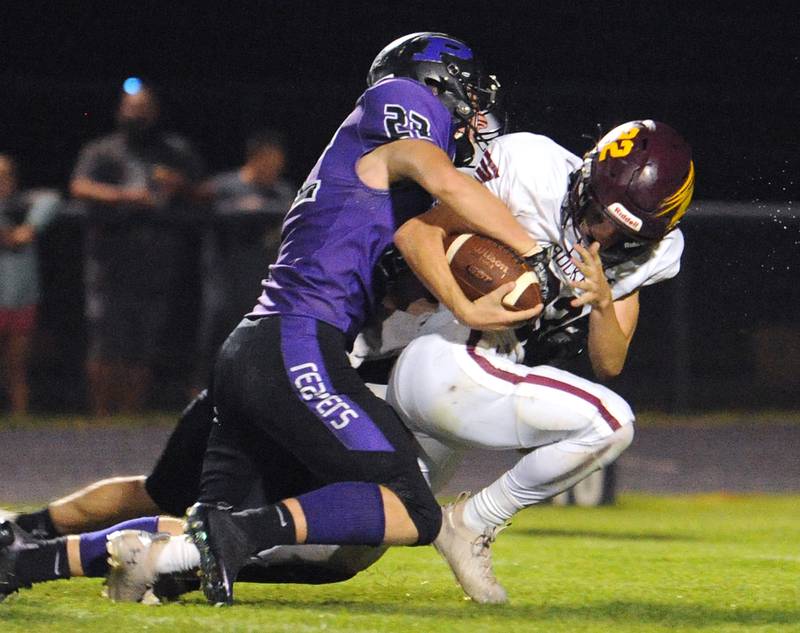 Richmond-Burton wingback Landon Jacoby (22) secures a catch as he is hit by Plano linebacker Sean Earwood (22) during a varsity game at Plano High School on Friday.