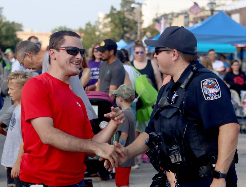 Crystal Lake Police Officer Tyler Kendall, right, greets Matt Lukas of Crystal Lake during National Night Out activities in downtown Crystal Lake on Thursday, Aug. 7, 2025.