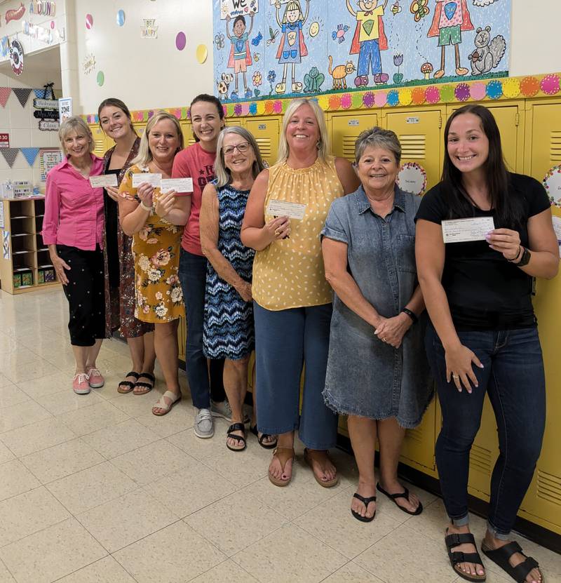 Oregon Community Unit School District first grade teachers receive checks from the Mt. Morris Community Library Foundation to buy books for first grade students this year. Pictured, left to right, are: Foundation member Sandra Stengel, teachers Olivia Phalen, Dawn Merrill, Erica Cann, Foundation President Julie Robinson, teacher Gretchen Nelson, Foundation member Paula Diehl, and teacher Kenzie Dusing.