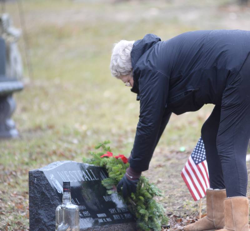 Vicky Travis of Oregon places a wreath at her dad's grave, David Westfall, during the Wreaths Across America event at Daysville Cemetery. east of Oregon, on Saturday, Dec. 16, 2023.