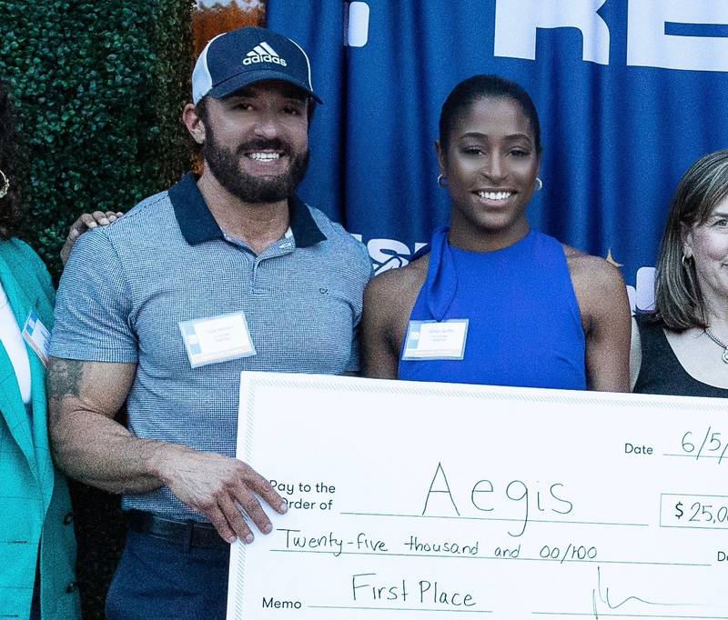 Peter Nicholos, left, and Tamika Vantifflin pose with a $25,000 check from a successful business competition.