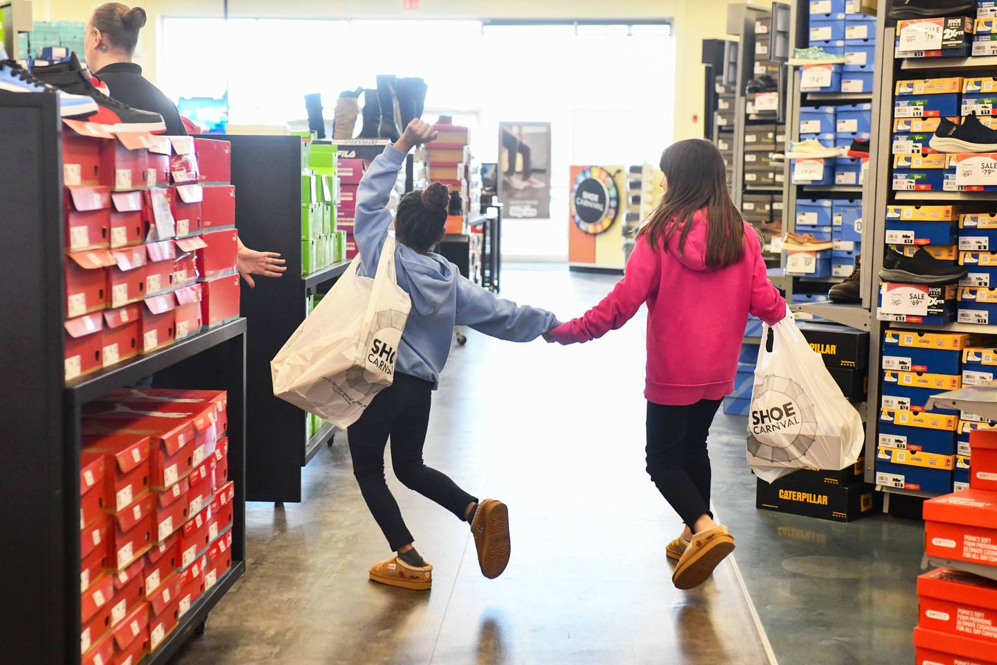 Two Steuben Elementary students skip and hold hands after choosing matching pairs of shoes at Shoe Carnival as part of the Kankakee Kiwanis Club's annual “All God’s Children Must Have Shoes” event on Feb. 27, 2025.