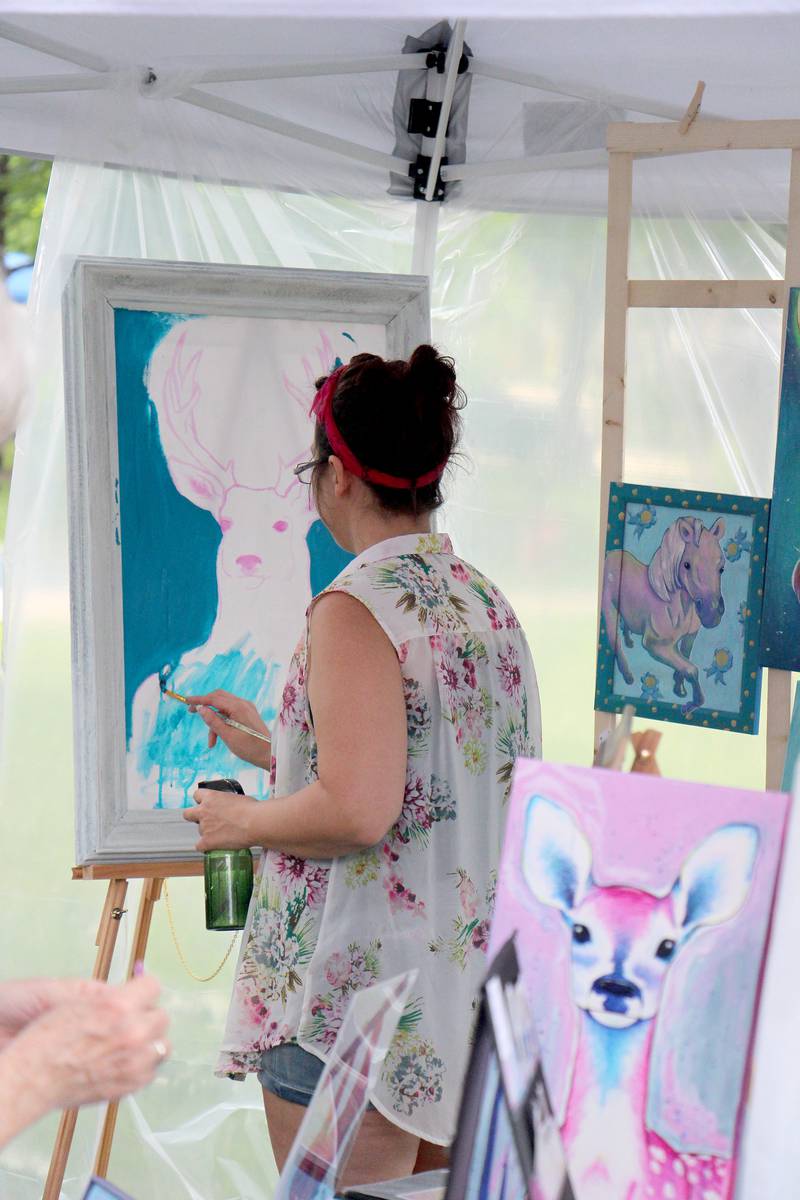 Whitley Cuevas works on a painting Saturday, July 1, 2023 during in her booth at Dixon Petunia Fest’s Nuts About Art. Cuevas had several works on display for sale and show.