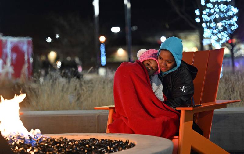 Layla McLemore, 2, snuggles with her mom, Simone McLemore, of Bourbonnais, on Thursday during the inaugural tree lighting at The Grove.