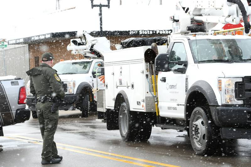 An Ogle County sheriff's deputy watches as ComEd crews turn down a street in Byron following a house fire on Saturday morning. The town of 3,700 was without power after a downed power line on W. Third Street was the apparent cause of a house fire.
