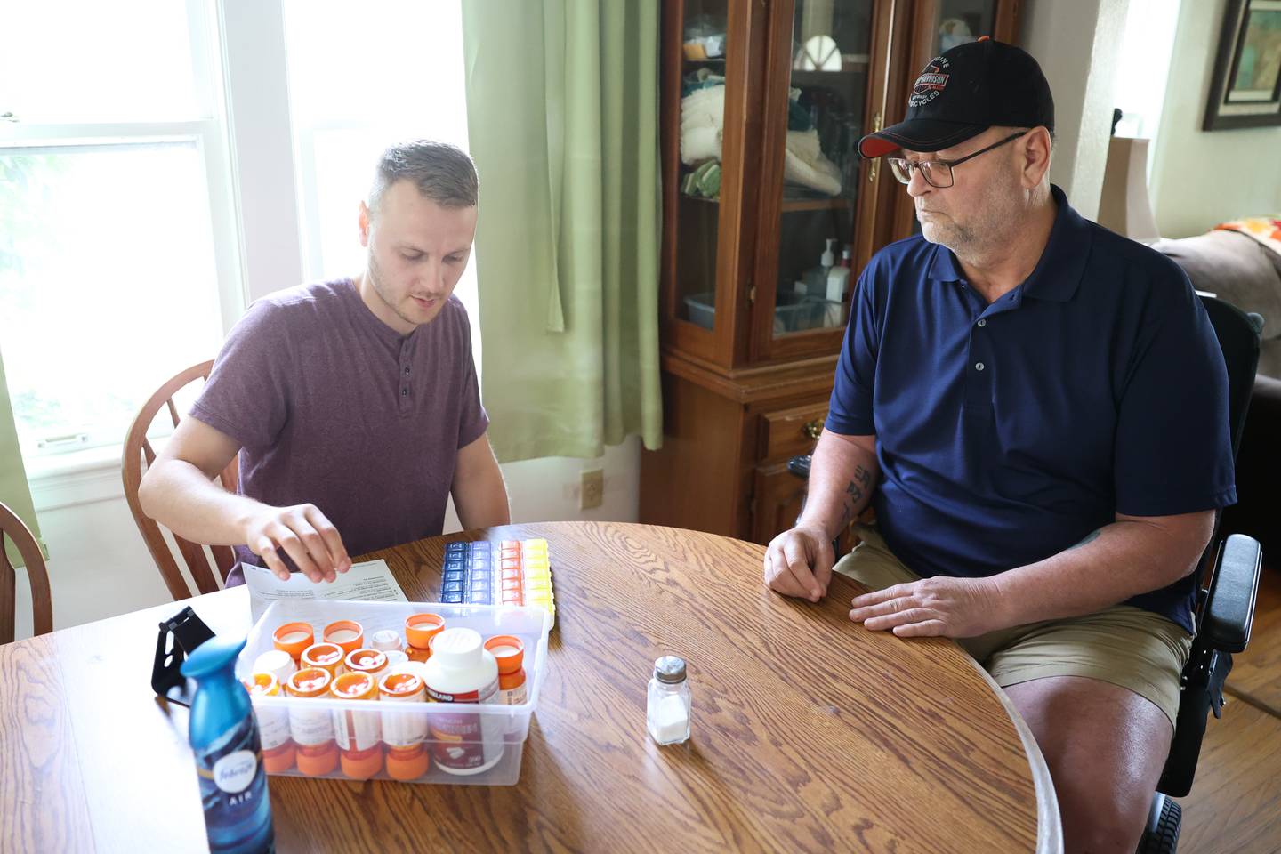 Sean Flannery, left, prepares Tim’s evening medicine. Nearly a year after Tim’s motorcycle accident that left him in critical condition, Tim is still recovering with the help of his son and wife. Wednesday, June 15, 2022 in Joliet.