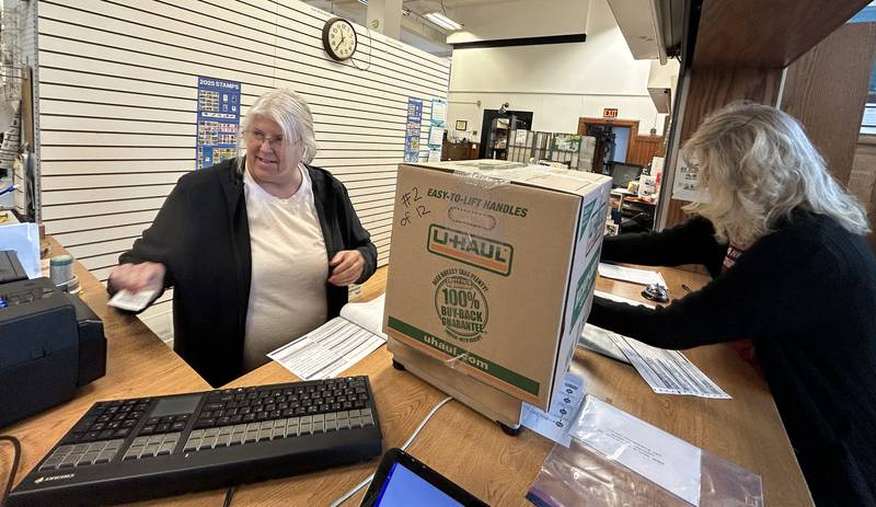 Mt. Morris Post Master Amy DeVries (left) weighs one of the 12 boxes filled with care packages headed to sailors on the USS Fitzgerald as Joyce Long, chairman of the Outreach Team for the Evangelical Free Church of Mt. Morris, completes paperwork  on Thursday, Oct. 16, 2025.