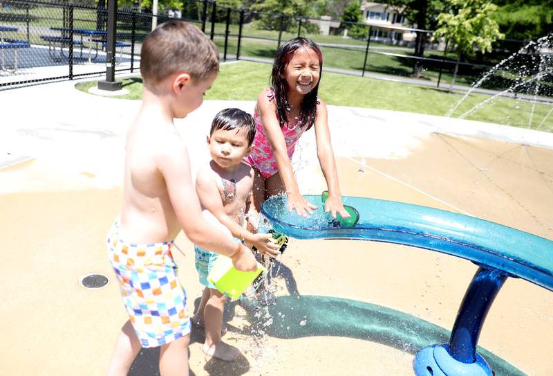 (Left to right) Donovan DeBore, 4, Angel Flores, 2, and Evelyn Flores, 7, play in the water at the Downers Grove Park District’s Adventure Falls Sprayground at McCollum Park on Friday, June 14, 2024.