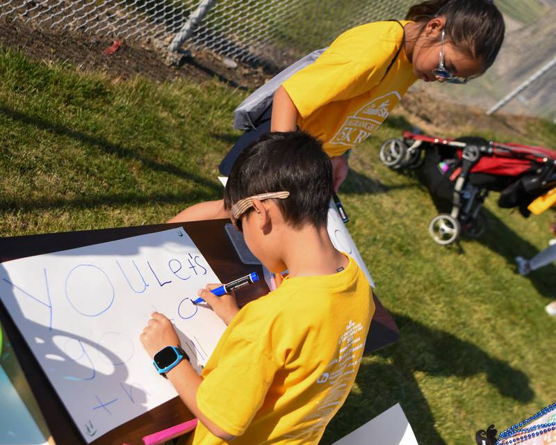 Brandon, 7 years old, and sister Brianna Wong, 11 years old, make signs before the start of the Leadershop 5k run-walk held in Le Grange on Friday June 9, 2023.