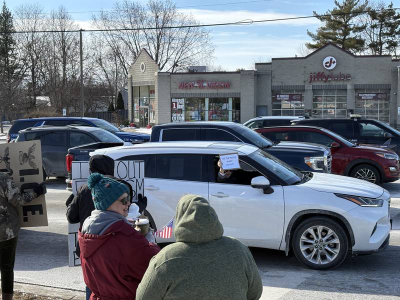 A passenger in a car holds a sign against ICE at a protest in McHenry Feb. 1, 2026.