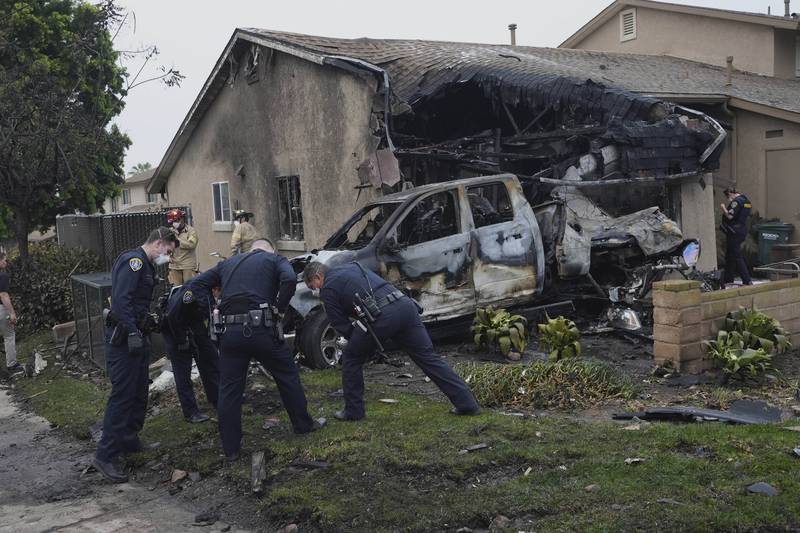 Authorities work the scene where a small plane crashed into a San Diego neighborhood, setting several homes on fire and forcing evacuations along several blocks early Thursday, May 22, 2025. (AP Photo/Gregory Bull)