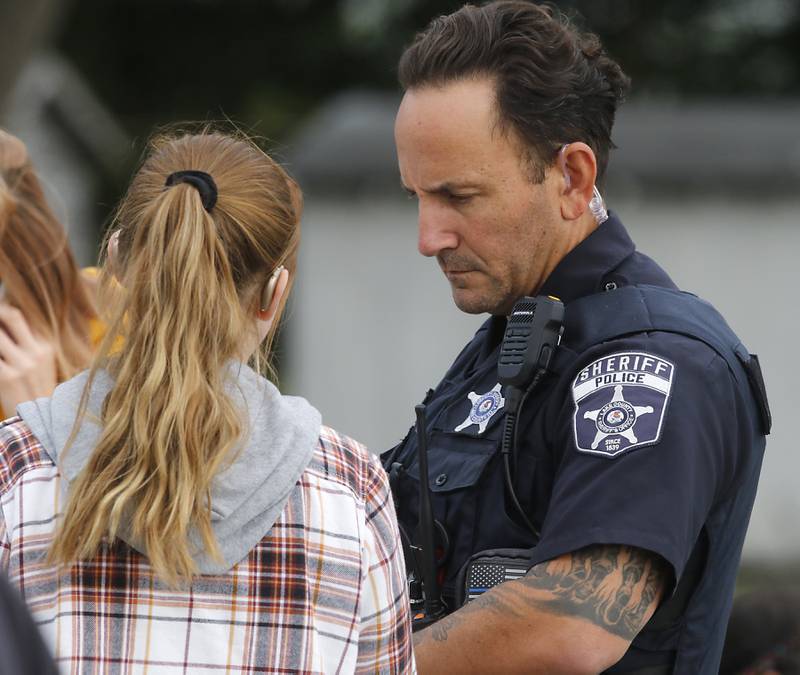 A Lake County Sheriff deputy talks with a home as divers from the Antioch Fire Protection District and a sonar team from the Illinois Department of Natural Resources continue searching Tuesday, Oct. 7, 2025, on Fox Lake near Antioch for a man thrown from a boat he was test driving Monday night.