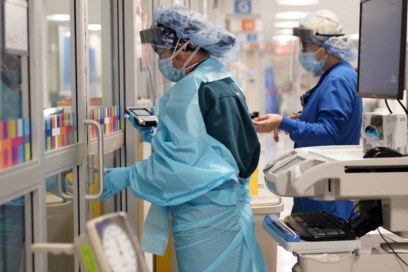 FILE - In this Oct. 28, 2020, file photo, medical personnel don PPE while attending to a patient (not infected with COVID-19) at Bellevue Hospital in New York. Workers in New York City-run hospitals and health clinics will have to get vaccinated or get tested weekly under a policy announced Wednesday, July 21, 2021, to battle a rise in COVID-19 cases fueled by the highly contagious delta variant.  (AP Photo/Seth Wenig, File)