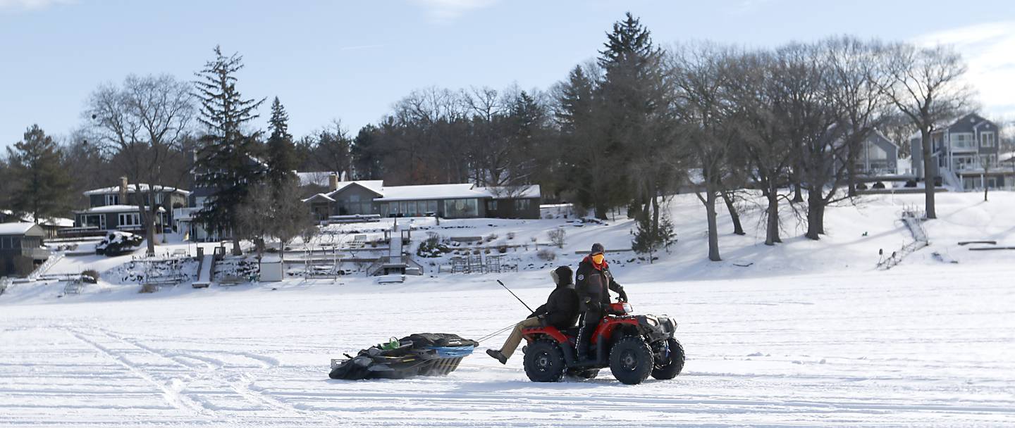 Two fishermen change locations while ice fishing Friday, Feb 3. 2023, on Petite Lake near Fox Lake.