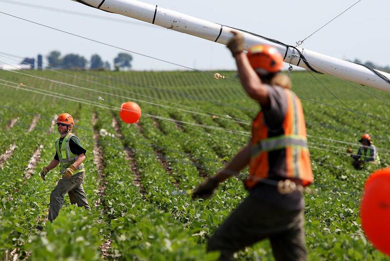 Contractors (from left:) Remmington Fox, Michael Williams, and Michael Sibalski work on erecting a wind testing tower on Monday, July 17, 2017 in a soy bean field on MacQueen Road in South Grove.  The tower, also known as a MET (meteorological evaluation tower), is one of two highly contested structures at recent county and zoning meetings.