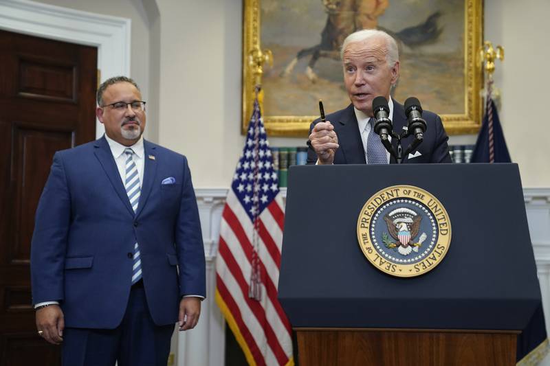 President Joe Biden speaks in the Roosevelt Room of the White House, Friday, June 30, 2023, in Washington. Education Secretary Miguel Cardona listens at left. The Biden administration is moving forward on a new student debt relief plan after the Supreme Court struck down his original initiative to provide relief to 43 million borrowers. (AP Photo/Evan Vucci)