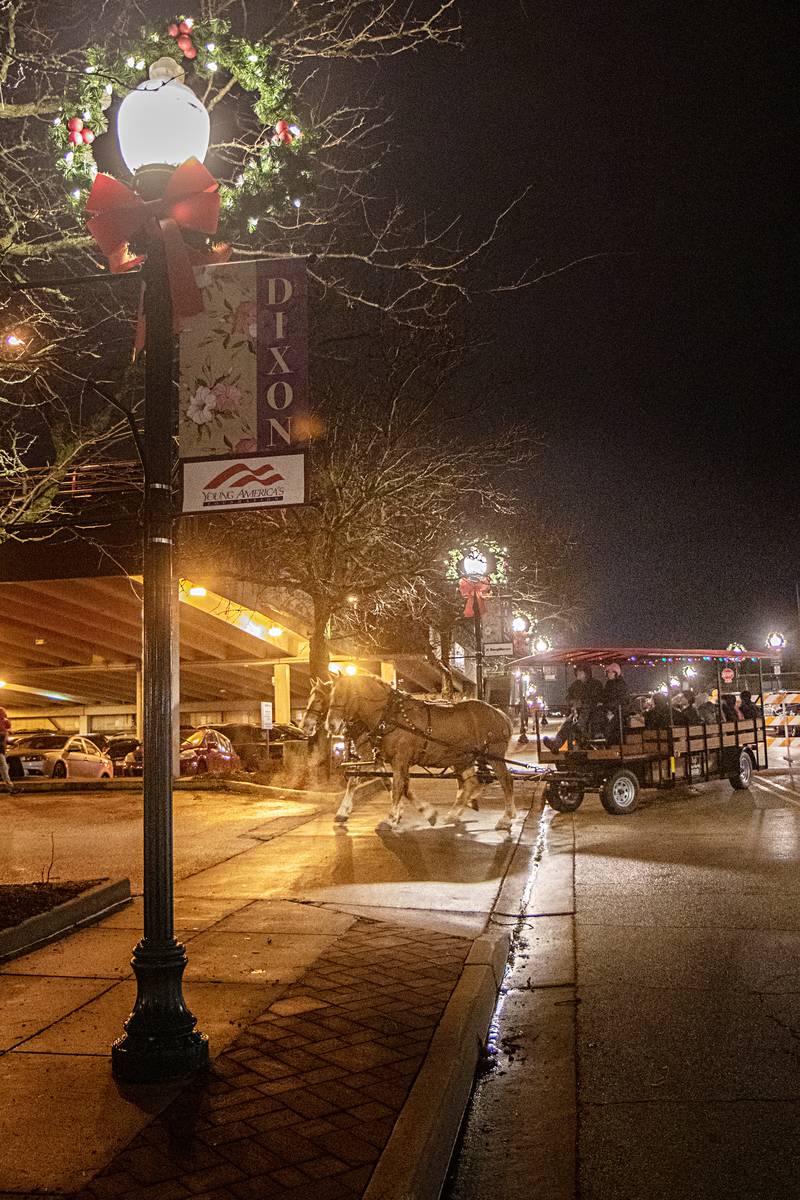Horse drawn carriages take visitors through the holiday wonderland of Dixon Friday, Dec. 1, 2023.