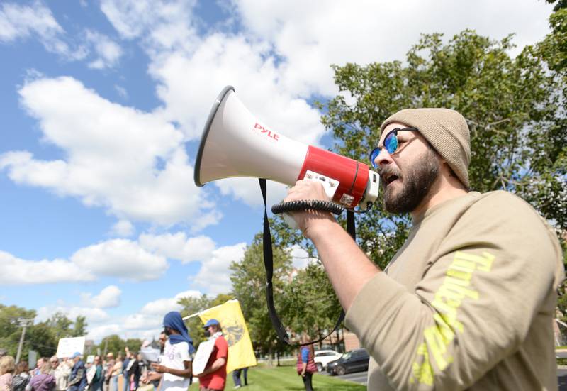 Sean Rowe of Bensenville leads a demonstrators in chants Sept. 7 during a protest outside the Hampton Inn & Suites in Downers Grove where ICE agents are staying.