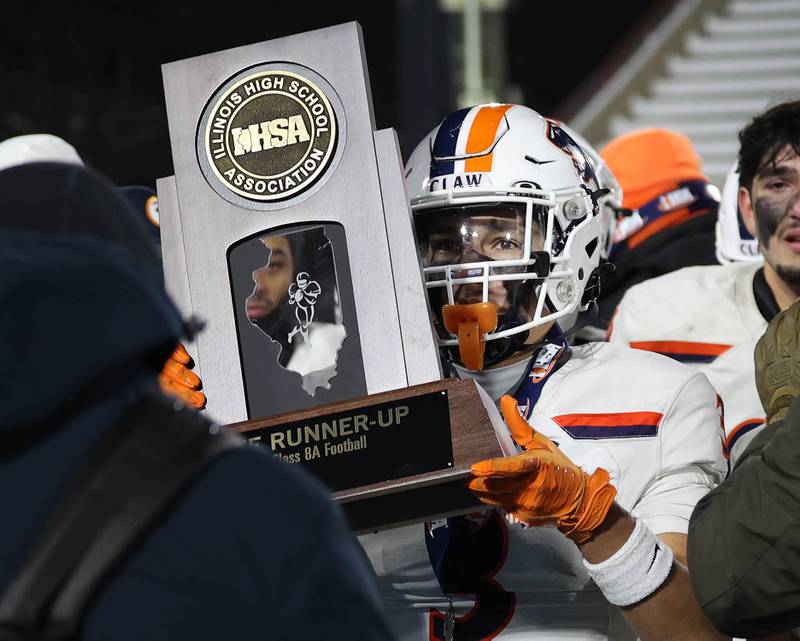 Oswego's Devin Mata holds the state runner-up trophy Wednesday, Dec. 3, 2025, after their loss to Mount Carmel in the IHSA Class 8A state chamionship game in Huskie Stadium at Northern Illinois University in DeKalb.