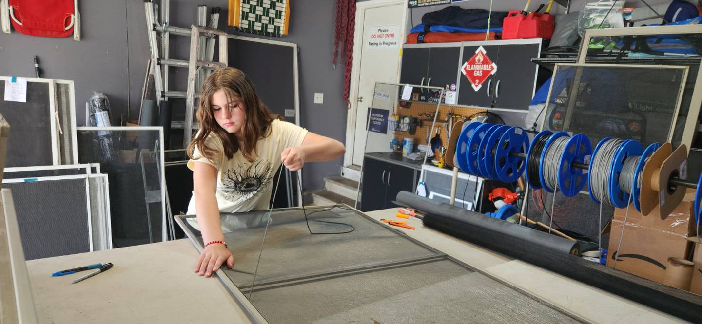 Sophia Gentile, 11, of Romeoville, helps repairs screens in her garage. Her brother Dante Gentile started the screen repair business four years ago to help pay for Boy Scout activities. Sophia Gentile sometimes helps to pay for her Girl Scout activities.