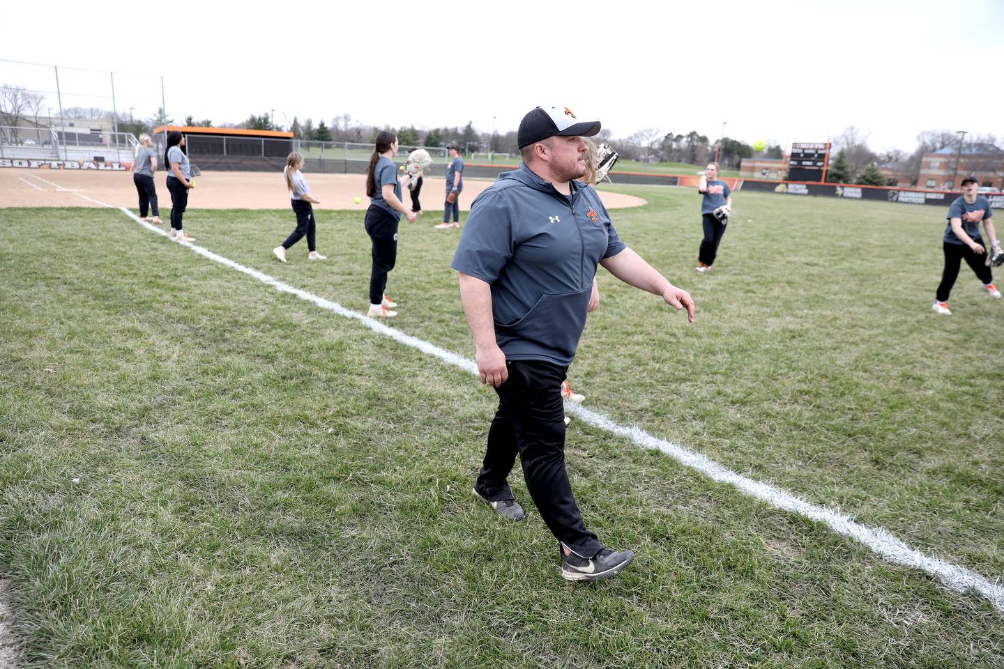 Assistant Coach Max Payleitner, a graduate of St. Charles schools, works with the St. Charles East varsity softball team during a recent practice at the school. Payleitner is also a teacher in St. Charles School District 303.