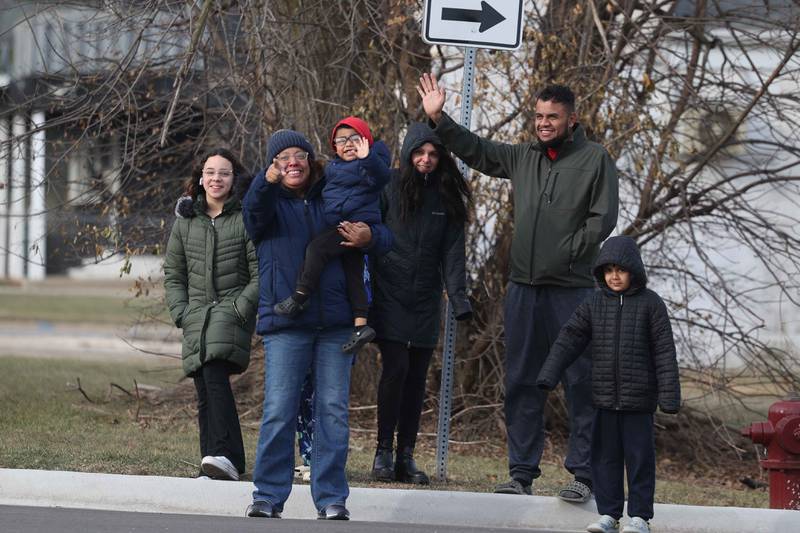 A family waves to Santa as the Joliet police, fire and public works vehicles escort Santa through Joliet before he heads off to the North Pole for the annual Santa Send-Off on Saturday, Dec. 14, 2024 in Joliet.