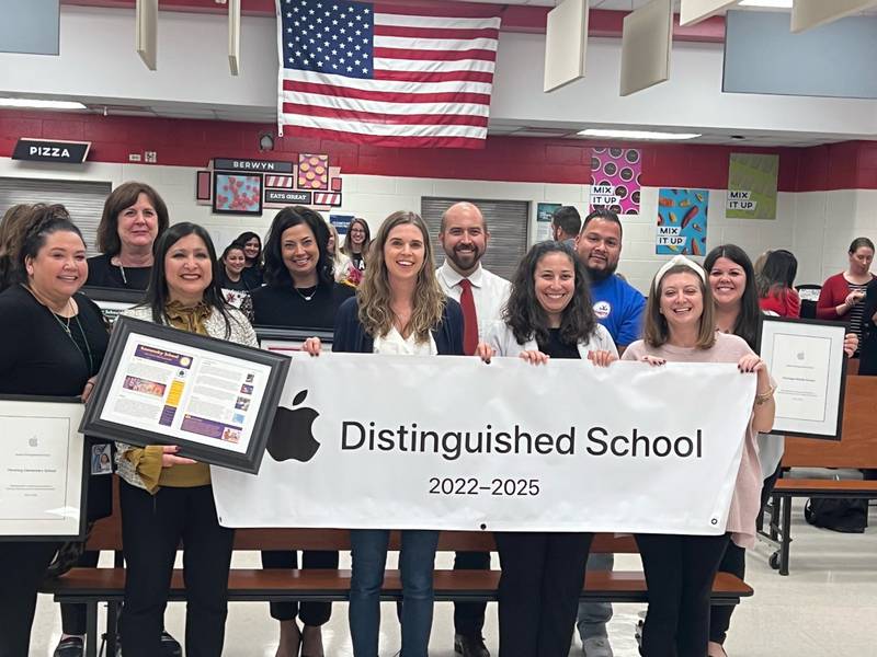 Members of the Berwyn South District 100 administration and staff display a banner and plaque indicating that all district schools received Apple Distinguished Schools designations. (Photo courtesy of Berwyn South District 100)